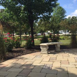 A peaceful park scene with a stone bench, surrounded by trees and flowers.