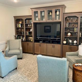 A cozy living room with a large entertainment center surrounded by bookshelves and comfortable seating.