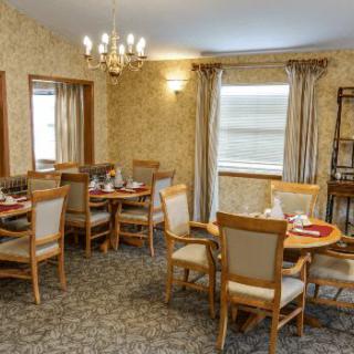 A cozy dining room with neatly arranged tables and chairs, adorned with a chandelier and elegant decor.