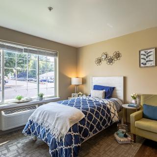 A cozy bedroom with a single bed and large window letting in natural light.