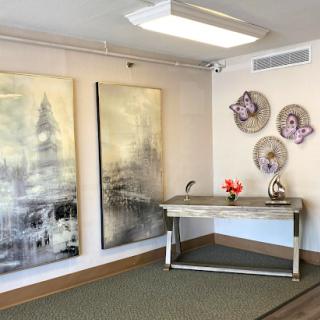 A modern interior space featuring large abstract paintings, decorative plates on the wall, and a stylish desk with a flower arrangement.