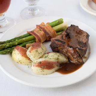 A plate featuring a juicy steak, roasted potatoes, and bacon-wrapped asparagus.