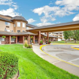 A scenic view of a hotel building with lush greenery and a bright blue sky.
