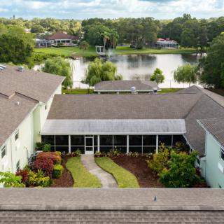 Aerial view of a residential house with a well-kept backyard garden and a scenic lake in the background.