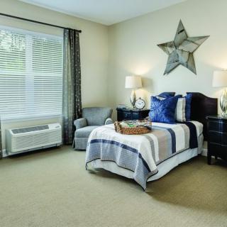 A modern bedroom with stylish decor, featuring a neatly made bed, star-shaped wall art, and cozy lighting.