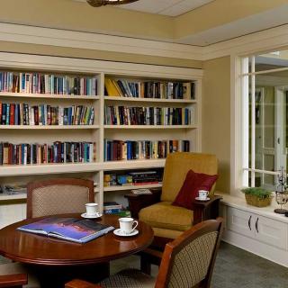 A cozy reading room with bookshelves, armchairs, and a coffee table.