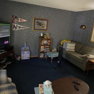 A cozy living room with a TV, couch, and various decorations including pennants and wall art.