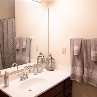 A neatly organized bathroom with a sink, mirror, and decorative elements.