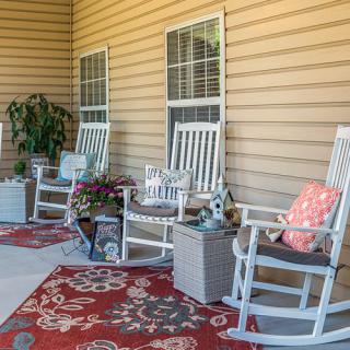 A cozy porch with rocking chairs, potted plants, and decorative rugs.