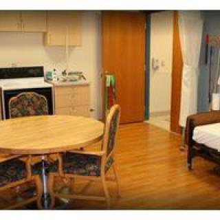 A cozy room with a small kitchenette, dining table, and bed.