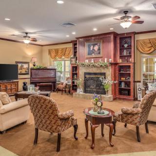 A spacious and elegantly furnished living room featuring a fireplace, seating area, television, and built-in bookshelves.