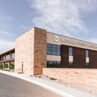 A modern medical office building with a brick facade under a clear sky.