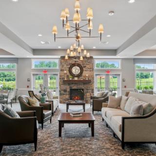 A spacious and elegantly designed living room featuring a large chandelier, comfortable sofas, a fireplace, and ample natural light from multiple windows.