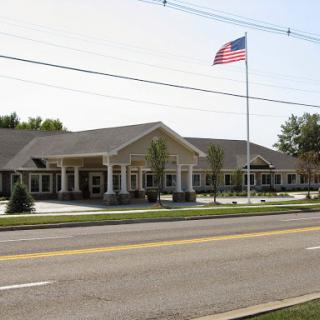 A community center featuring an American flag flying in front, set against a clear blue sky.