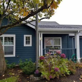 A charming blue house with a front garden featuring hydrangeas.