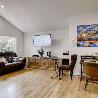 A spacious living room with a comfortable sofa, wooden flooring, and a wall-mounted television.
