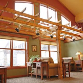 A cozy interior space with wooden beams, large windows, and comfortable seating areas.
