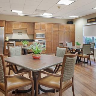 A spacious kitchen and dining area with tables, chairs, and decorative plants.
