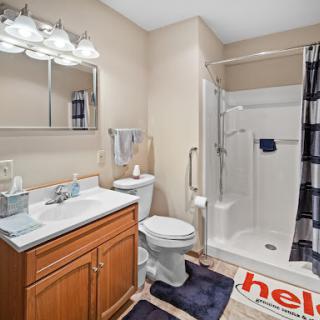 A well-lit bathroom featuring a shower, toilet, and modern vanity.