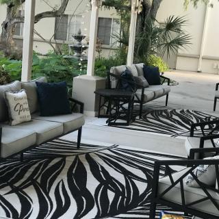 A stylish outdoor patio setup with sofas, chairs, and a patterned rug.