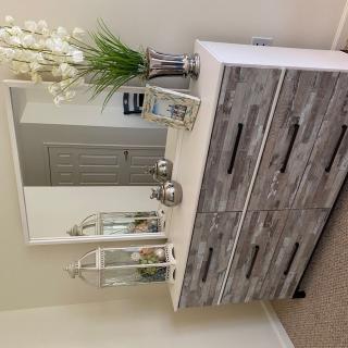 A stylish dresser with a mirror adorned by flowers and decorative items in a beautifully decorated bedroom.