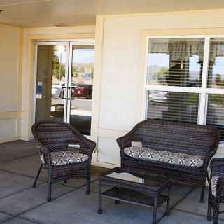 A small outdoor seating area with wicker furniture outside a building's entrance.