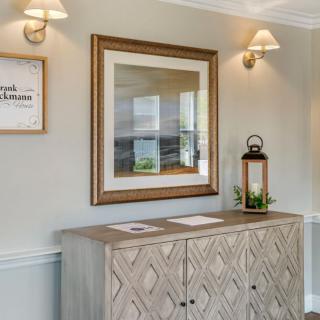 A stylish hallway interior featuring a wooden cabinet, framed artwork, and decorative lamps.