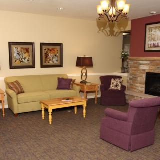 A cozy living room with a sofa, armchair, and fireplace.