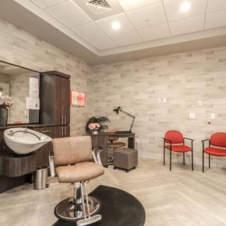 A modern hair salon interior with a styling chair, mirror, and sink, alongside a cozy waiting area.