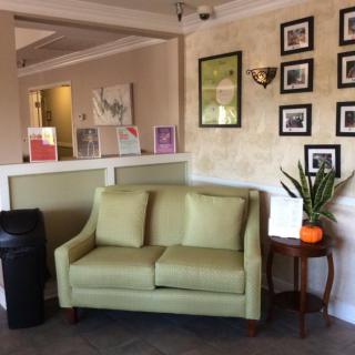 A cozy lobby area with a green sofa and decorative wall art.