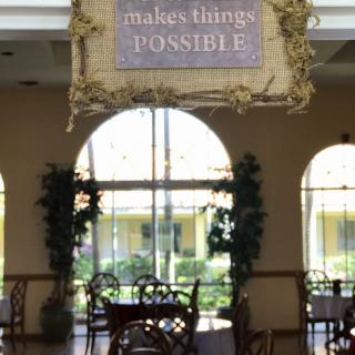 A cozy cafe interior with a motivational quote hanging above tables and chairs.
