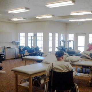 A rehabilitation room with patients in wheelchairs engaging in physical therapy exercises.