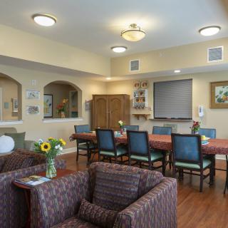 A cozy living room featuring a large table with chairs, comfortable seating, and warm lighting.