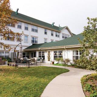 A view of a multi-story building with a green roof, surrounded by a well-maintained garden and outdoor seating.