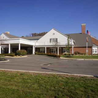 A suburban building with a covered entrance and driveway under a clear blue sky.
