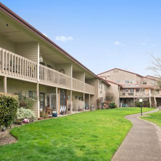 A well-maintained two-story apartment complex with balconies and a lush green lawn.