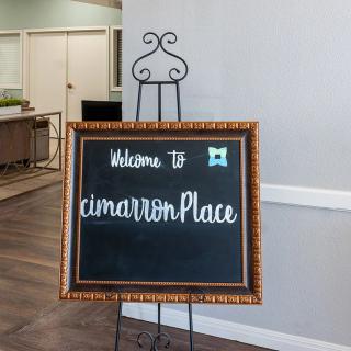 Welcome sign at Cimarron Place displayed on a decorative chalkboard inside a building.