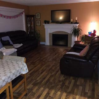A cozy living room with sofas and a fireplace, featuring a television above the mantel.