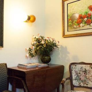 A cozy interior features vintage furniture, floral decor, and wall art.