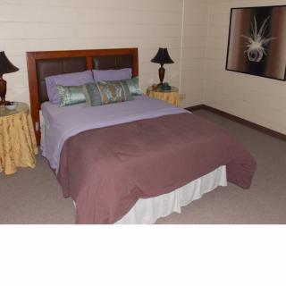 A cozy bedroom featuring a neatly made bed with pillows, side tables with lamps, and artwork on the wall.