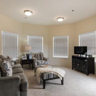 A cozy living room with modern furnishings, featuring a sofa, armchair, and a television.