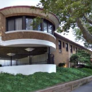 A modern building with rounded architectural features surrounded by trees and greenery.
