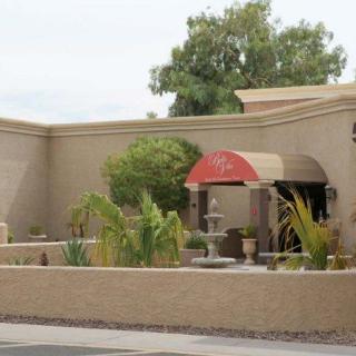 A building with a red awning, surrounded by plants and featuring a fountain.