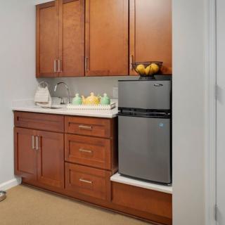 A compact kitchen area with wooden cabinets and a small refrigerator.