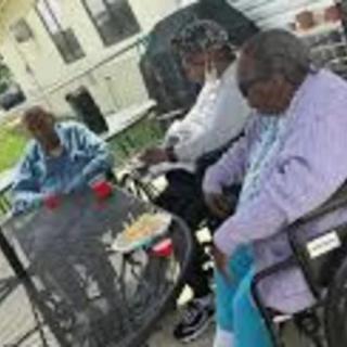 A group of people sitting outside at a table, engaged in conversation.