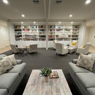 A cozy living room with comfortable seating and a large bookshelf backdrop.