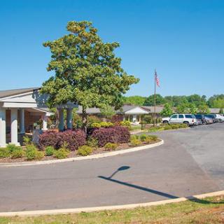 A well-maintained building surrounded by greenery and a clear blue sky.