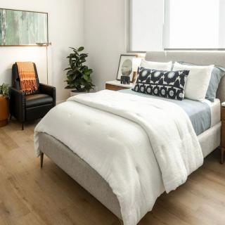 A modern bedroom with stylish decor, featuring a comfortable bed, decorative pillows, and a cozy chair.