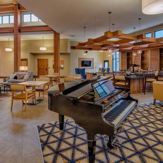 A modern lounge interior featuring a grand piano surrounded by comfortable seating and stylish lighting.
