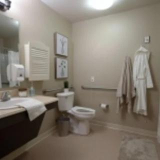 A modern bathroom with a sink, toilet, and hanging robes.